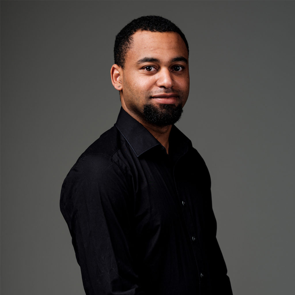 Yoran Vroom is drummer bij Marmoucha Orchestra. Yoran staat op deze foto voor een grijze muur.